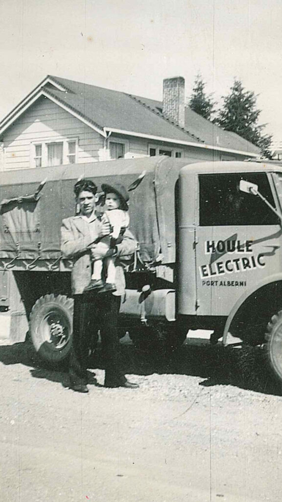 Lionel Houle and his child in 1952 standing in front of a Houle Electric truck.