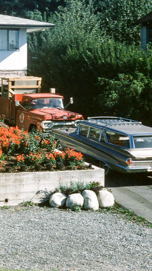 2 cars parked in a driveway in the 1960s