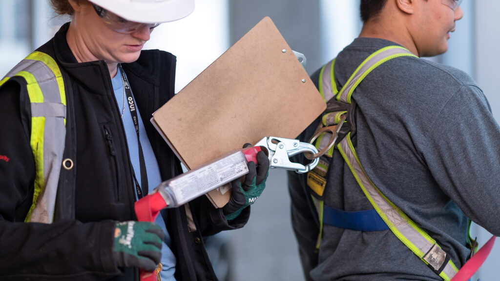 A supervisor checking the safety equipment of a team member