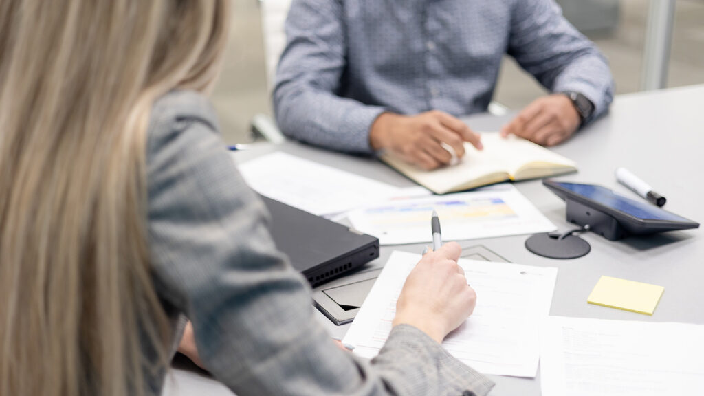 Two office employees collaborating over a number of reports