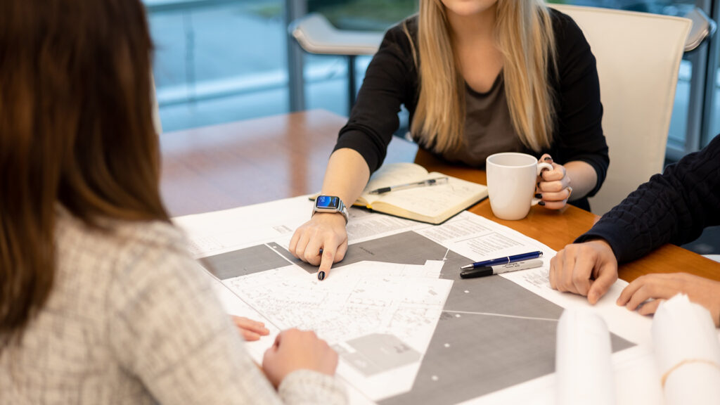 Group of employees discussing over electrical drawings