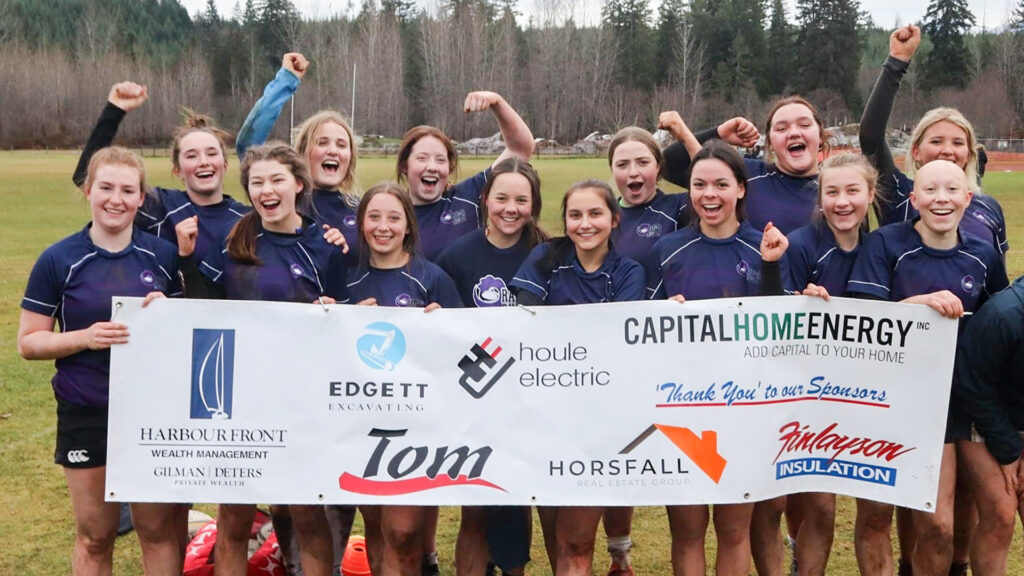 Girls rugby team holding up sponsorship banner and cheering.