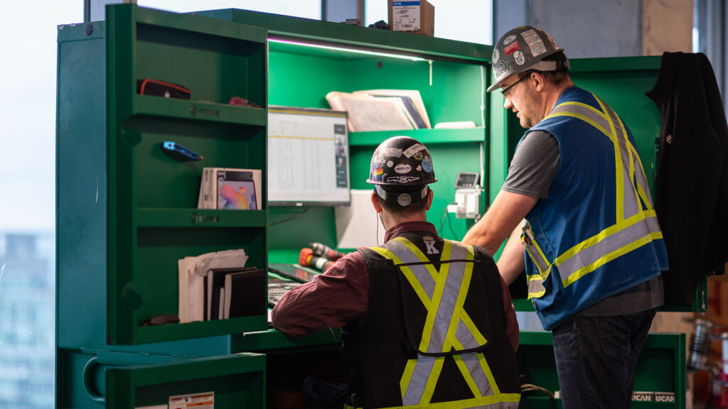 Two Houle employees talking at a work station on site.