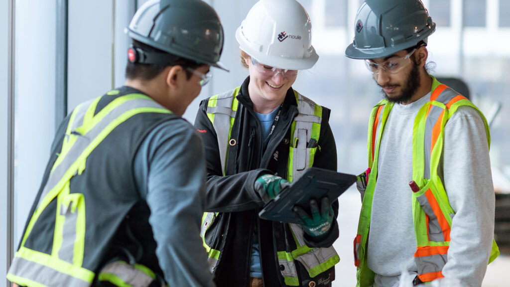 Three Houle employees gathering around a tablet device on site.